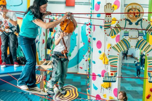 Beneficiar al programului Climb Again depășind obstacole pe peretele de escaladă la Climb Again